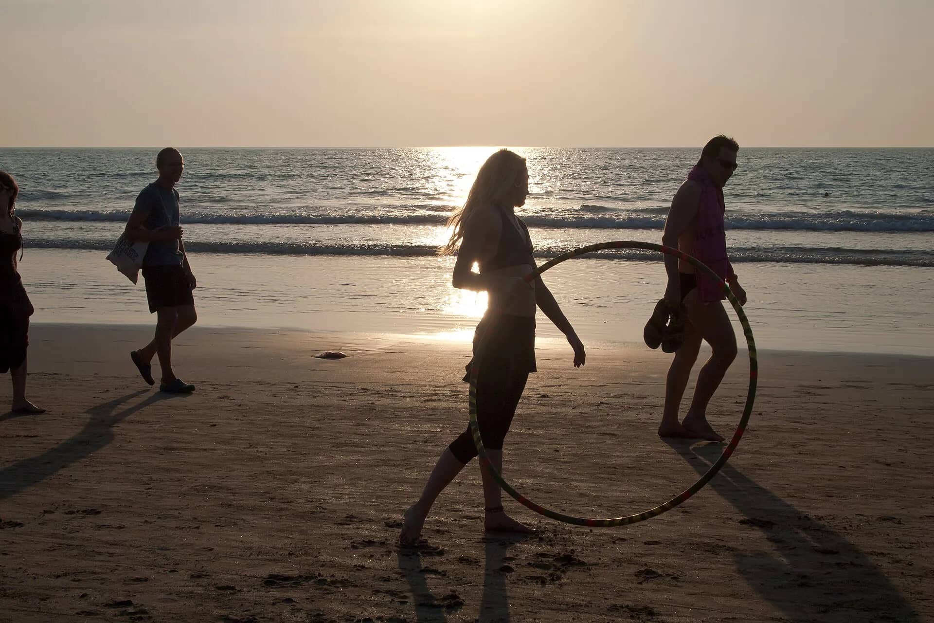 Performers with hula hoops on the beach at sunset
