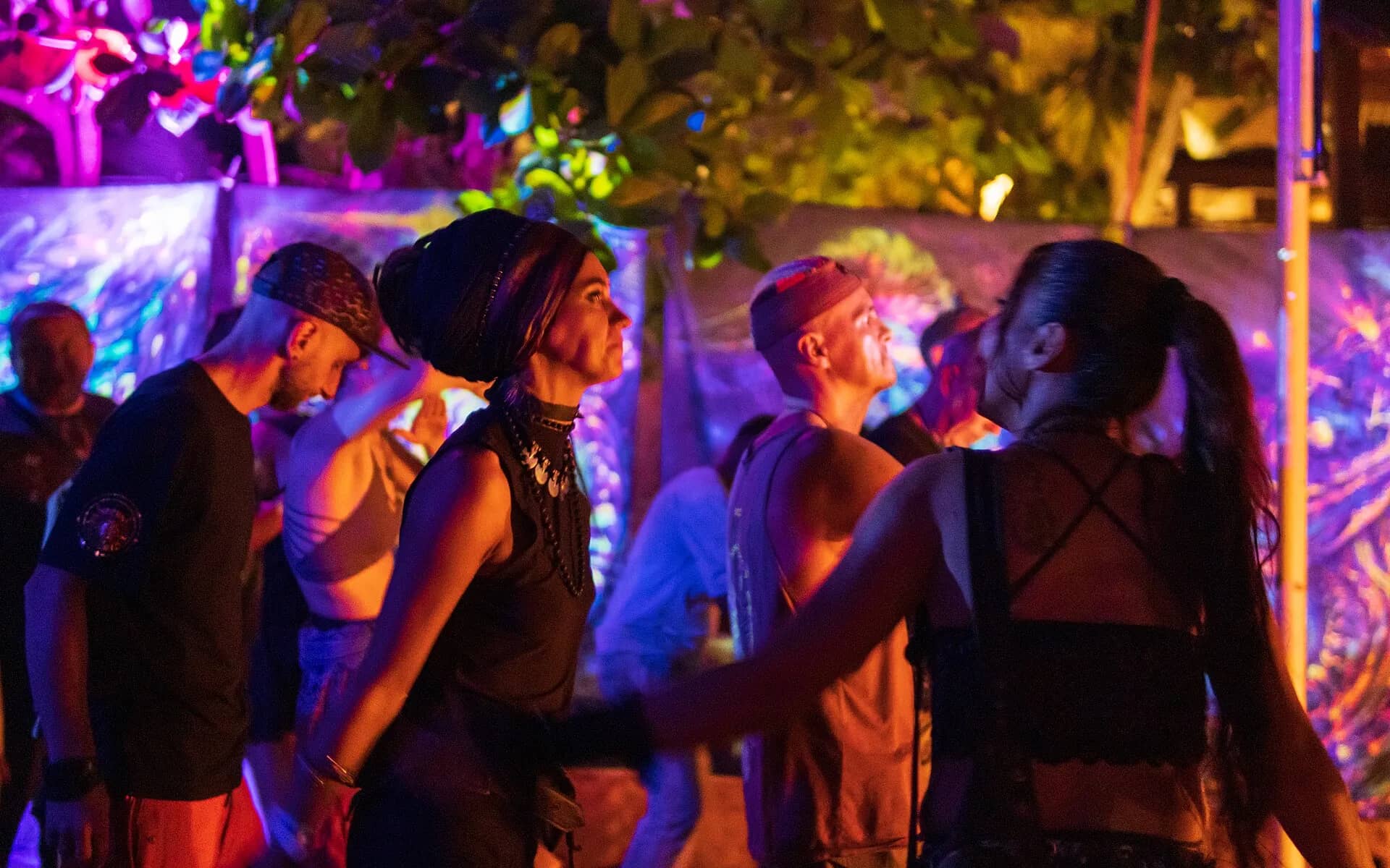 Friends dancing under neon lights at a beach party in Goa